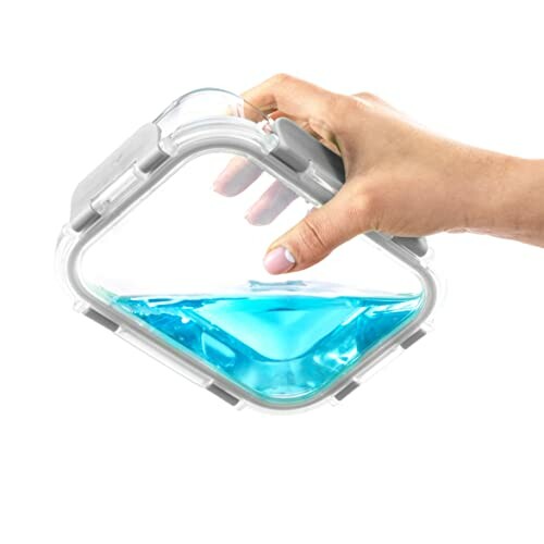 Hand holding a leakproof container with blue liquid.