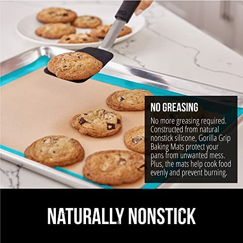 Baking sheet with cookies on nonstick mat and spatula.